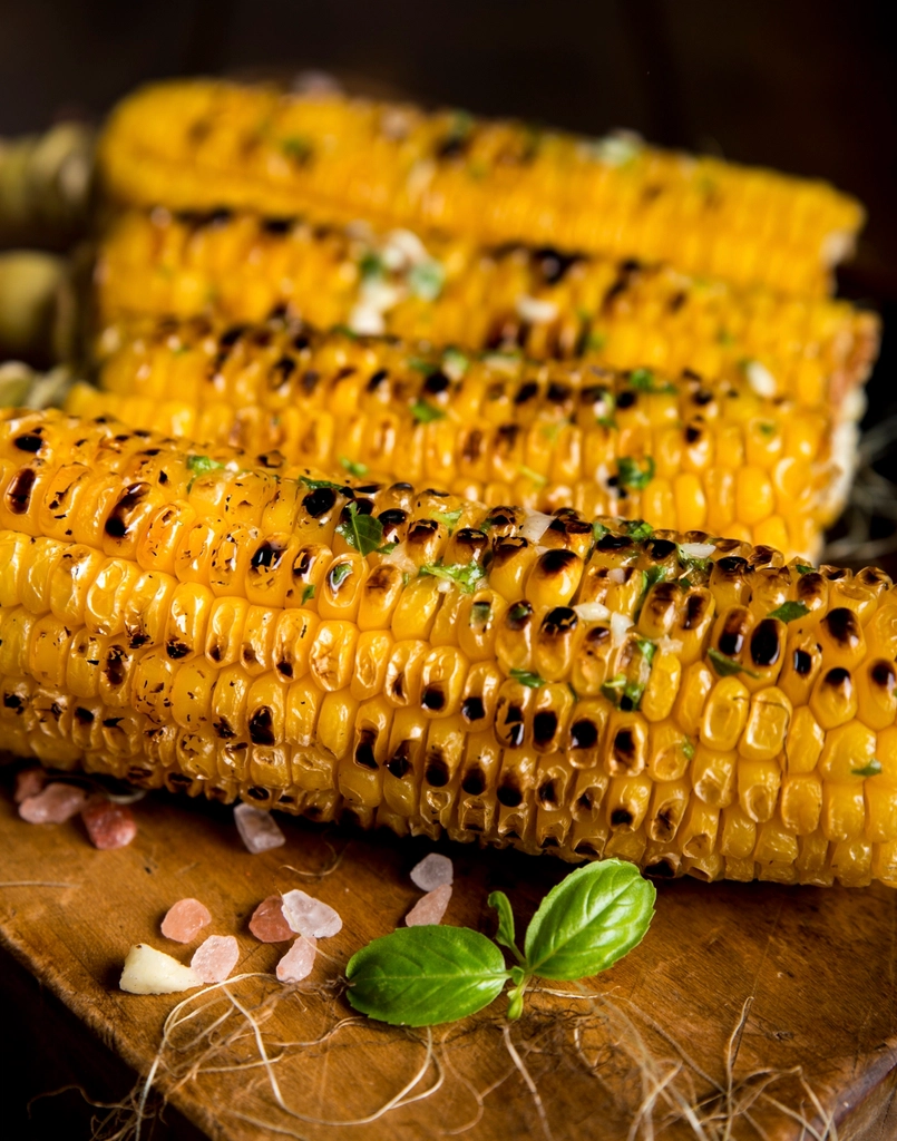 Close-up of freshly roasted sweet corn cobs, charred and glistening